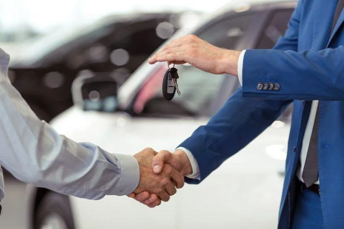 A car dealership representative handing over a vehicle